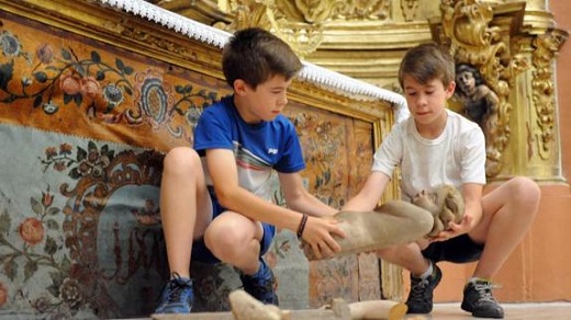 Dos monaguillos retiran del suelo uno de los angelotes caídos. 