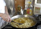 Un cocinero fríe patatas para tortilla. 