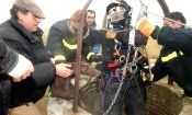 Un bombero, atado por un arnés, sale del pozo con uno de los perros rescatados.