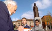 El escultor Santiago de Santiago firma un autógrafo a dos niños con su obra al fondo. 