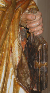 Detalle de la escultura de San Juan sosteniendo el evangelio dentro de una bolsa