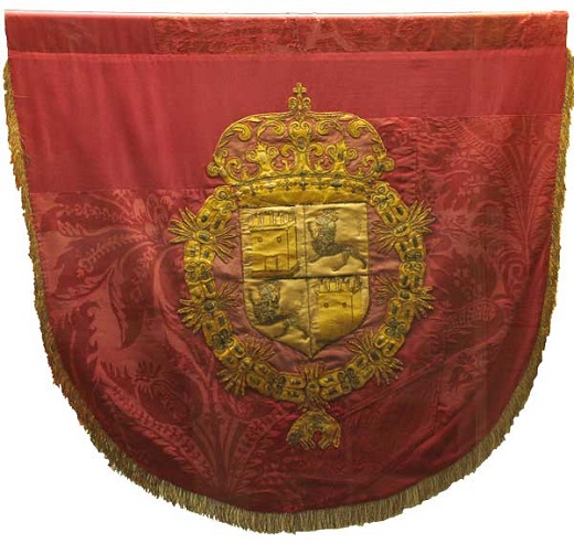 Estandarte Real de proclamaciones. Talleres de Medina del Campo. 1666 (estandarte) / Finales del siglo XV (escudos). Damasco y tafetán de seda; hilos metálicos entorchados de plata y plata dorada; láminas y lentejuelas de plata, hilos de seda / 93 x 108 cm (escudos: 66 x 50 cm).Colegiata de San Antolín. Medina del Campo (obra depositada en el Museo de las Ferias)