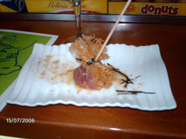 Descripción: Reducción de verdejo en dulce mechado en bola de mucuit albardado en jamón envuelto en hilo de pasta frito con legera crema cecial en cordón. Nombre: Perla de micuit rellena de gelatina de verdejo con jamón e hilo frito. Categoría: Caliente/Isabelino