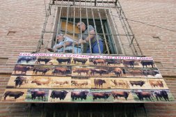 Dos operarios municipales colocan un cartel con los toros de la feria. / FRAN JIMNEZ