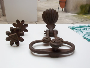Llamador realizado en forja artística, con aldaba de argolla y concha decorativa, con su herraje para golpear, con escudos.
