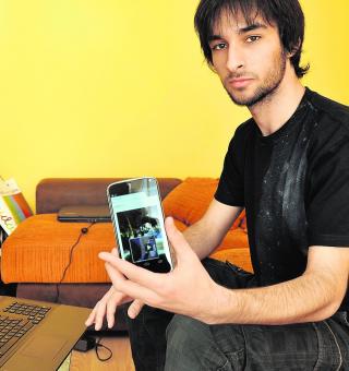 Adrián de la Rosa, en su domicilio, muestra el móvil con la aplicación. :: Fran Jiménez