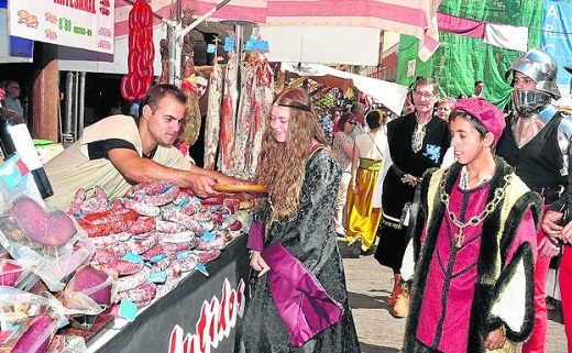 Participantes en la recreación histórica visitan uno de los puestos de la feria en Medina. / F. J.