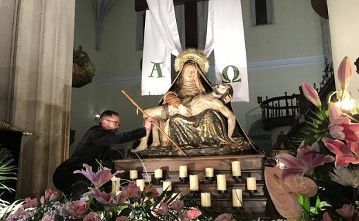 Un cofrade coloca el bastón de mando de la alcaldesa sobre el tablero de la imagen de la Virgen de las Angustias, en el interior del templo. / P. GONZÁLEZ