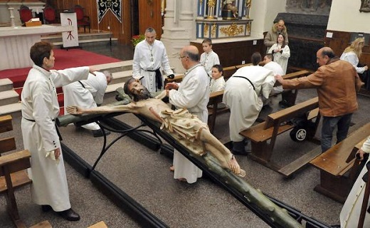 Los cofrades del Descendimiento secan la talla del Cristo en la iglesia de San Miguel. / FRAN JIMÉNEZ