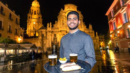 El camarero Luis Londoño del restaurante murciano Pasaje Belluga, posa con dos marineras, una tapa típica de Murcia, en la plaza Cardenal Belluga de Murcia. Al fondo la catedral - Efe