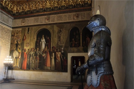 Isabel de Trastámara salió del @Alcazar_Segovia para ser proclamada en el atrio de la Iglesia de San Miguel. En el Salón de Embajadores existe una pintura que conmemora la coronación. Las figuras no tienen ojos. Ese día se celebraba Santa Lucía, patrona de los ciegos.