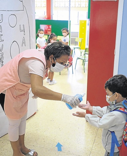 Una profesora pone gel desinfectante en las manos a un niño antes de entrar en la clase. /
EFE
